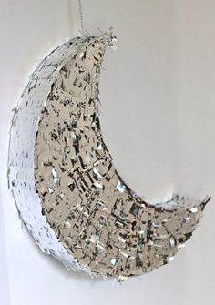 a paper moon hanging on the wall with silver foil sprinkles around it