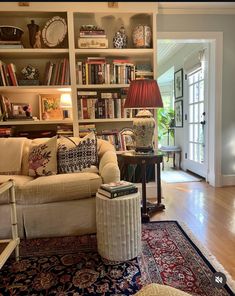 a living room filled with lots of furniture and bookshelves on top of a hard wood floor