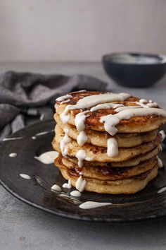 a stack of pancakes covered in icing on a black plate