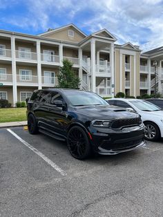 two dodge vehicles parked next to each other in a parking lot with apartment buildings behind them