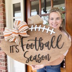 a woman holding up a football sign that says it's football season