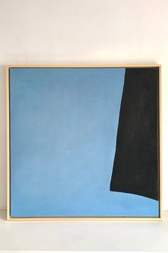 an abstract painting with blue and black in the middle on a white wall next to a shelf