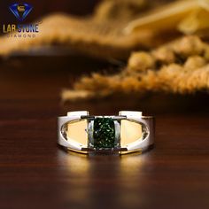 a ring with a green stone in the center on a table next to some dried plants