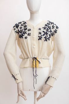 Classic Austrian style knitted wool blend cardigan. The cardigan features a rich floral embroidery. Fastens with plastic buttons, has a ribbon at the waist. Condition: Good vintage condition. There are few puffs, invisible while wearing. Fabric: wool blend Measurements: Best Fits: M All measurements are taken lying flat and have already been doubled. Shoulders: 46 cm / 18" Sleeves: 56 / 22'' Chest: 102 cm / 40" Length: 52 cm / 22" Spring Cream Knitted Cardigan, White Vintage Cardigan With Floral Embroidery, Spring Wool Sweater With Embroidery, Spring Wool Embroidered Sweater, Spring Embroidered Wool Sweater, Winter Embroidered Cream Cardigan, Cream Embroidered Winter Cardigan, Embroidered Cream Cardigan For Winter, Winter Cream Embroidered Cardigan