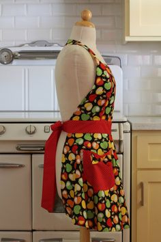 a mannequin wearing a colorful apron stands in front of a stove top oven