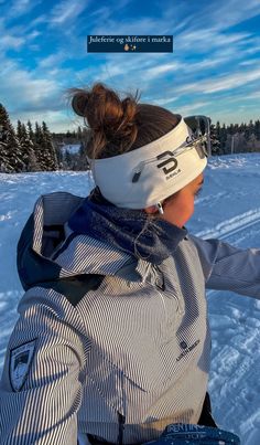 a woman riding skis on top of snow covered ground with trees in the background