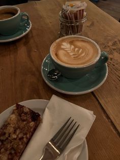 a cup of cappuccino on a table next to a piece of cake