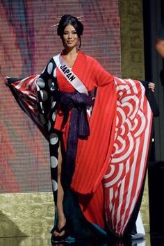 a woman in a red and black dress is standing on the stage with a large scarf around her neck