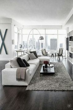 a living room filled with furniture and a large window covered in glass doors that look out onto the city