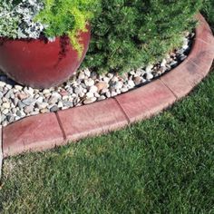 a red planter sitting on top of a lush green grass covered field next to a sidewalk