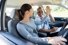 a man and woman sitting in the back seat of a car waving at each other