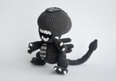 a crocheted black and white stuffed animal sitting on top of a white surface