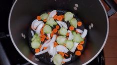 onions, carrots and celery being cooked in a wok on the stove