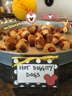 hot dogs with marshmallows and mustard on them are displayed in front of a mickey mouse sign