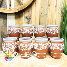 a group of brown and white pots sitting on top of a wooden table next to grass