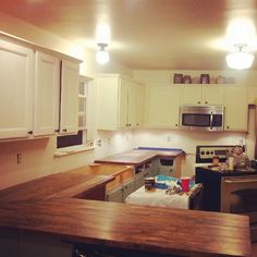 a kitchen with white cabinets and wooden counter tops