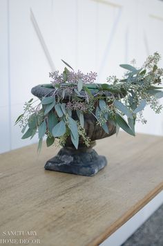 a vase filled with greenery sitting on top of a wooden table