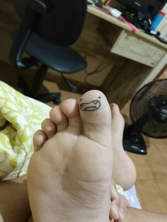 a person's foot with a smiley face drawn on the side of their toe