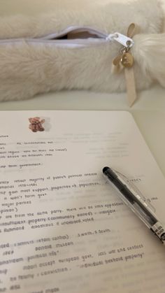 a pen sitting on top of a piece of paper next to a stuffed teddy bear