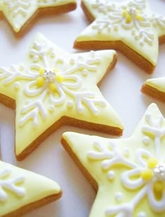 decorated cookies arranged in the shape of snowflakes on a white tablecloth with yellow icing