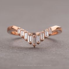 a rose gold wedding band with baguettes set in the middle, on a gray surface