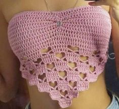 a woman wearing a pink crochet top with cut outs