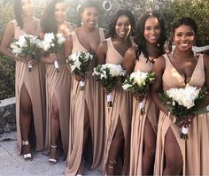 a group of women standing next to each other wearing dresses and holding bouquets in their hands