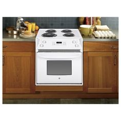 a white stove top oven sitting inside of a kitchen next to wooden cupboards and counter tops