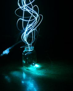 a glass jar with some lights in it on a dark surface next to a toothbrush