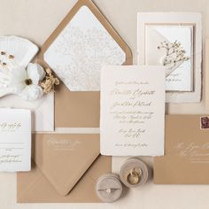 the wedding stationery is laid out on top of each other, including envelopes and rings