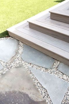 a stone walkway with steps leading up to the front door and grass in the background