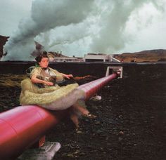 a woman sitting on top of a red pipe