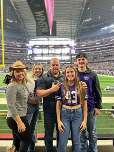 a group of people standing on top of a football field in front of a stadium