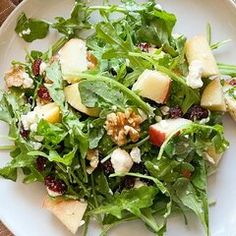 a white plate topped with salad and apple slices