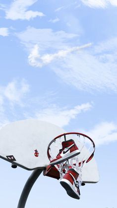 a basketball going through the hoop in front of a blue sky with white wispy clouds