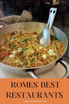 a pan filled with pasta and vegetables on top of a table next to a silver spoon