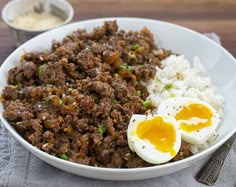 a bowl filled with rice, meat and eggs