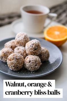 orange and cranberry bliss balls on a plate next to a cup of tea