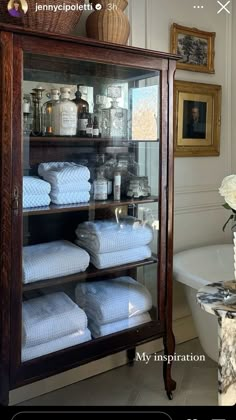 a display case filled with lots of white towels next to a bathtub and sink