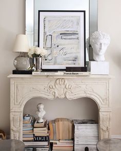 a white fireplace mantel with books and vases on top