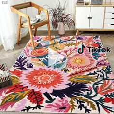 an area rug with flowers and leaves on it in the middle of a room next to a chair