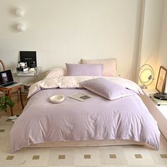 a bedroom with a bed covered in purple comforter and pillows on top of it