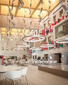 a large room filled with lots of white tables and chairs under chandelier hanging from the ceiling