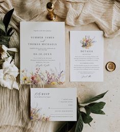 the wedding stationery is laid out with flowers and greenery