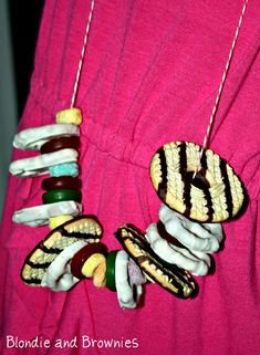 a woman wearing a pink dress and necklace made out of candy canes, marshmallows, and other candies