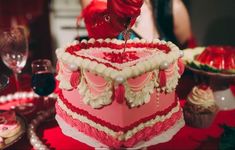 a large red and white cake sitting on top of a table next to wine glasses