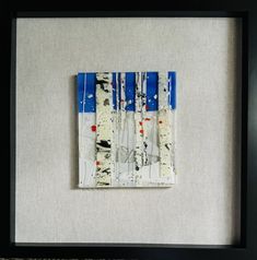 an art piece with blue and white paint on it, framed in a black frame