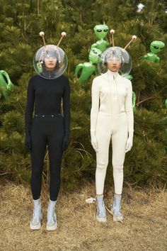 two mannequins wearing space suits in front of trees