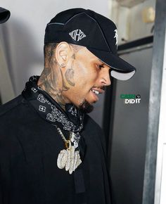 a man wearing a black hat with tattoos on his face and neck standing in front of a refrigerator