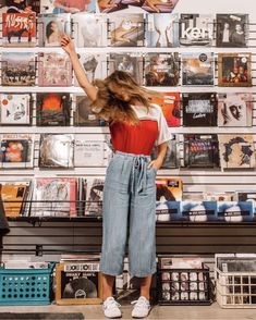 a woman standing in front of a wall full of records and cds with her hair blowing in the wind